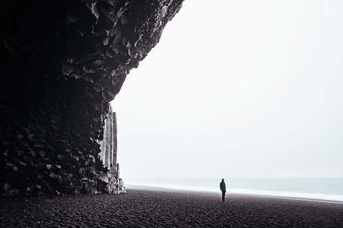 reynisfjara black sand beach person standing on shore during daytime white